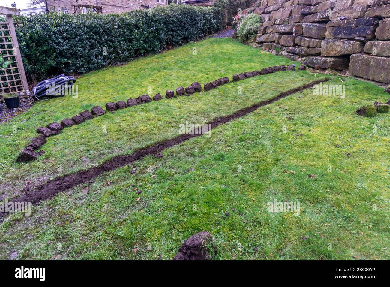Installazione di una trincea di drenaggio in un prato da giardino, Foto Stock
