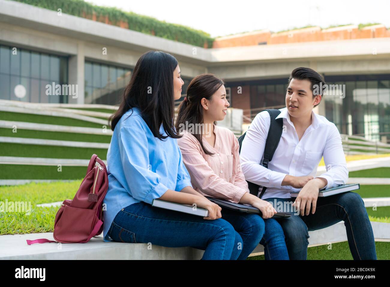 Tre studenti asiatici stanno discutendo di preparazione degli esami, presentazione, studio, studio per la preparazione dei test con il laptop dell'università. Istruzione, Lear Foto Stock