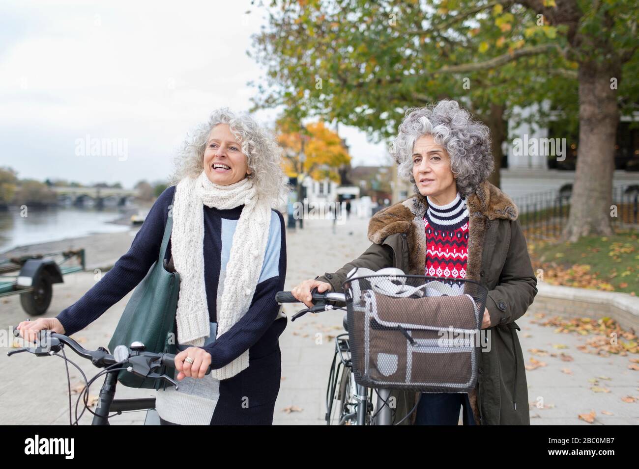 Donne anziane attive amici a piedi biciclette in autunno parco Foto Stock