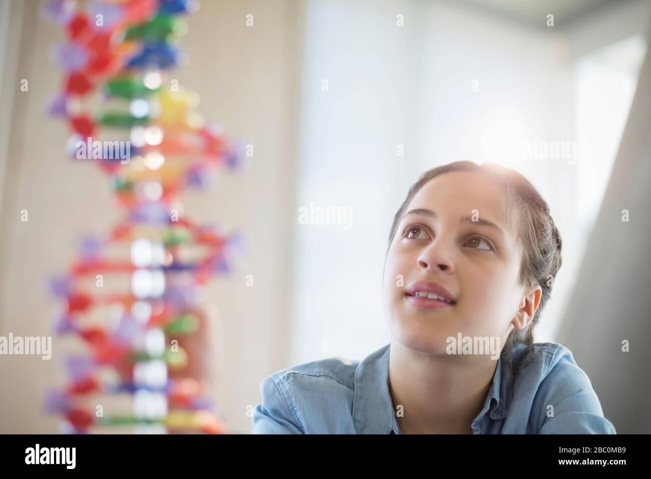 Studentesse di ragazza pensive che esaminano il modello di DNA in laboratorio di classe Foto Stock