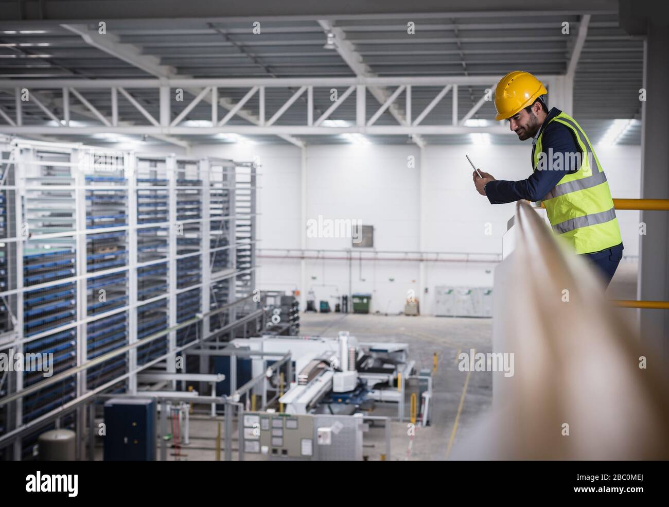 Supervisore maschile con appunti sulla piattaforma guardando verso il basso in fabbrica Foto Stock