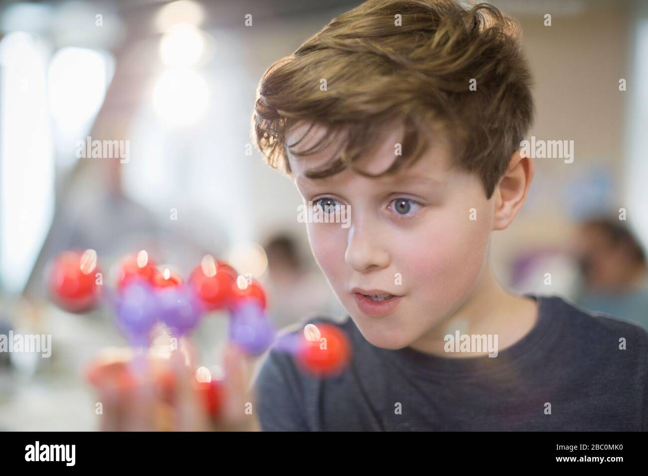 Ragazzo curioso che esamina il modello di molecola in classe di laboratorio Foto Stock