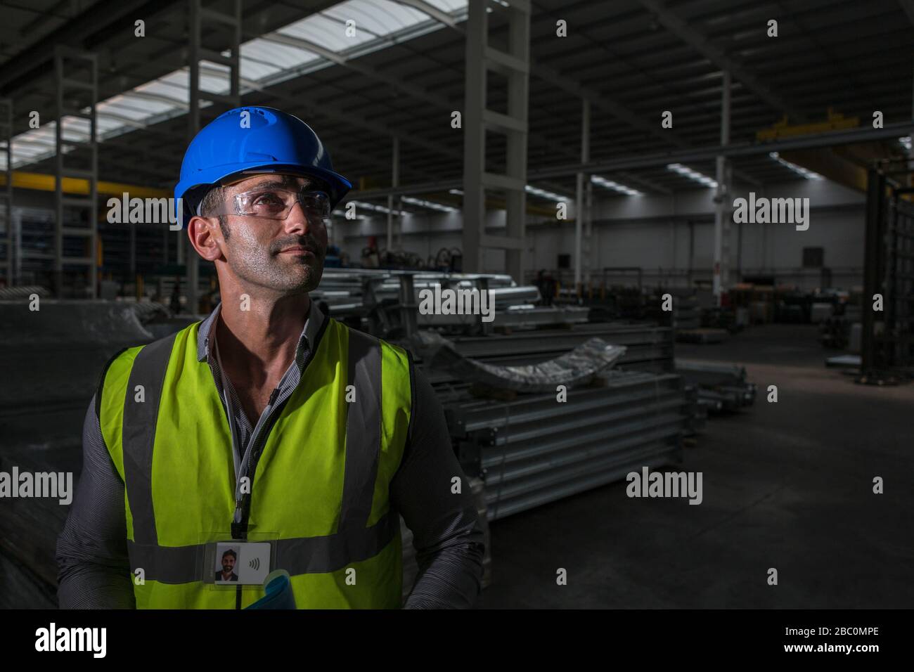 Ritratto lavoratore sicuro maschio guardando lontano in fabbrica oscura Foto Stock