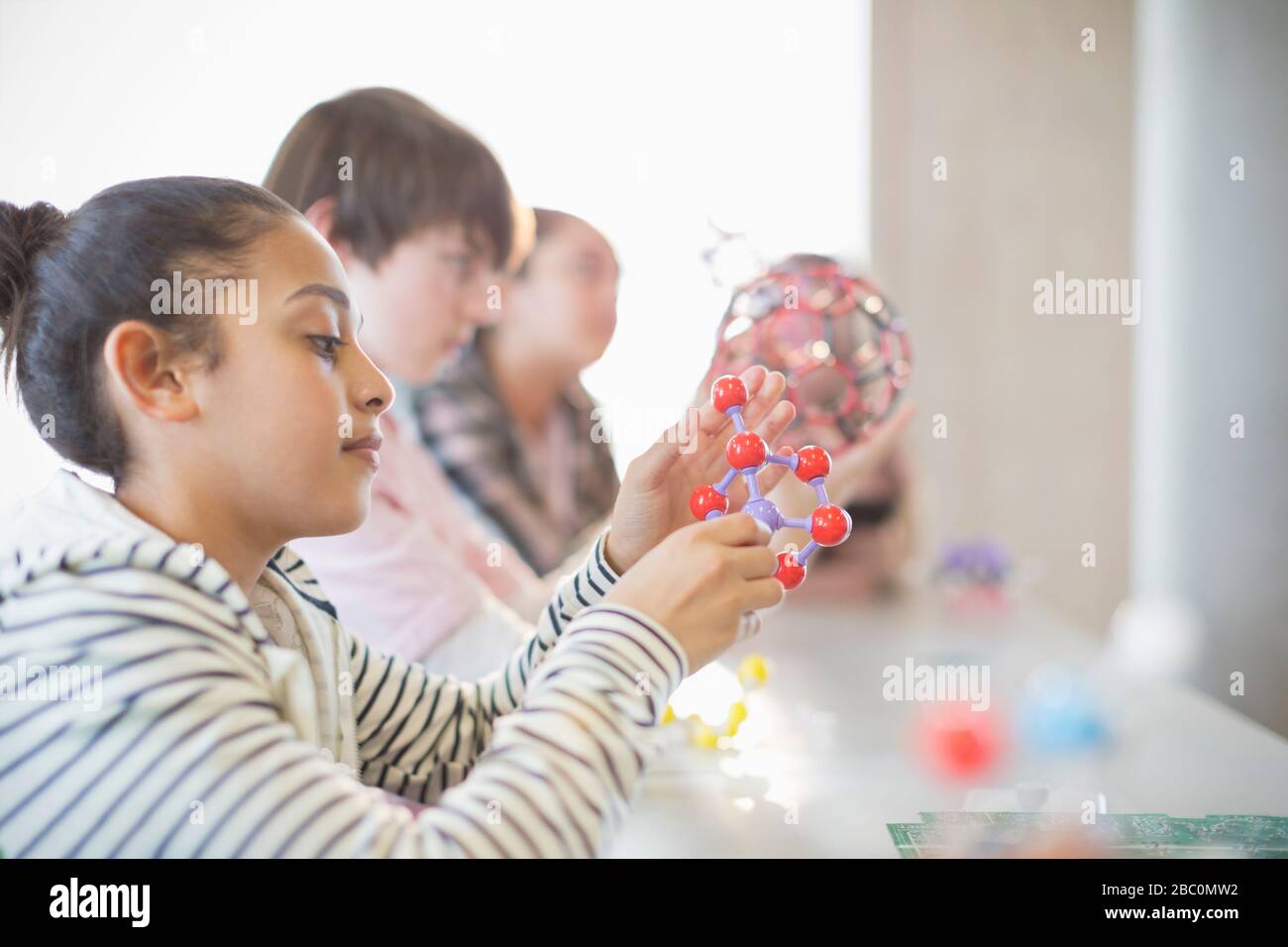Ragazza curiosa che esamina il modello di molecola in classe Foto Stock