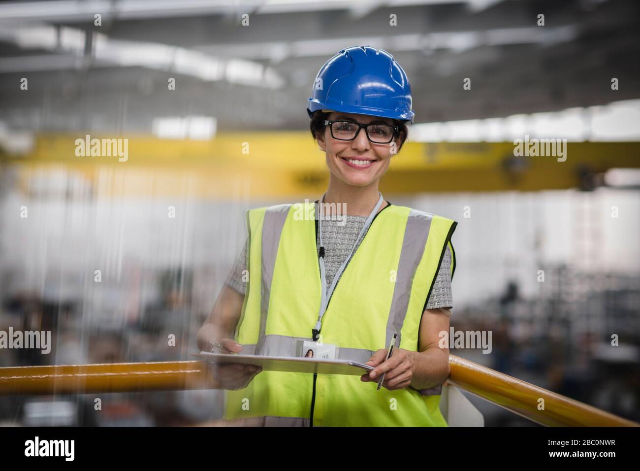 Ritratto sorridente, lavoratore sicuro con appunti sulla piattaforma in fabbrica Foto Stock