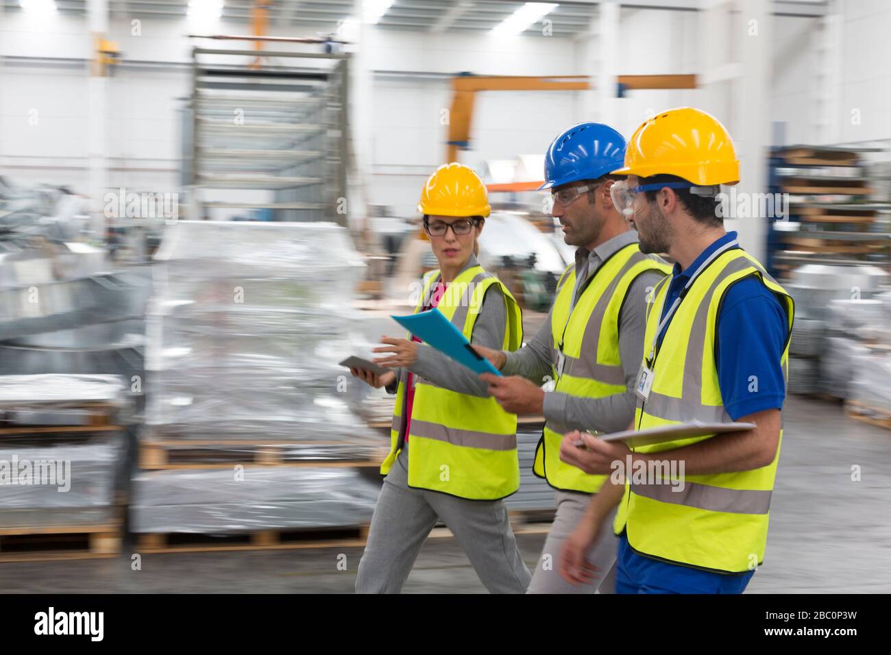 Supervisore e lavoratori che camminano e parlano n magazzino Foto Stock