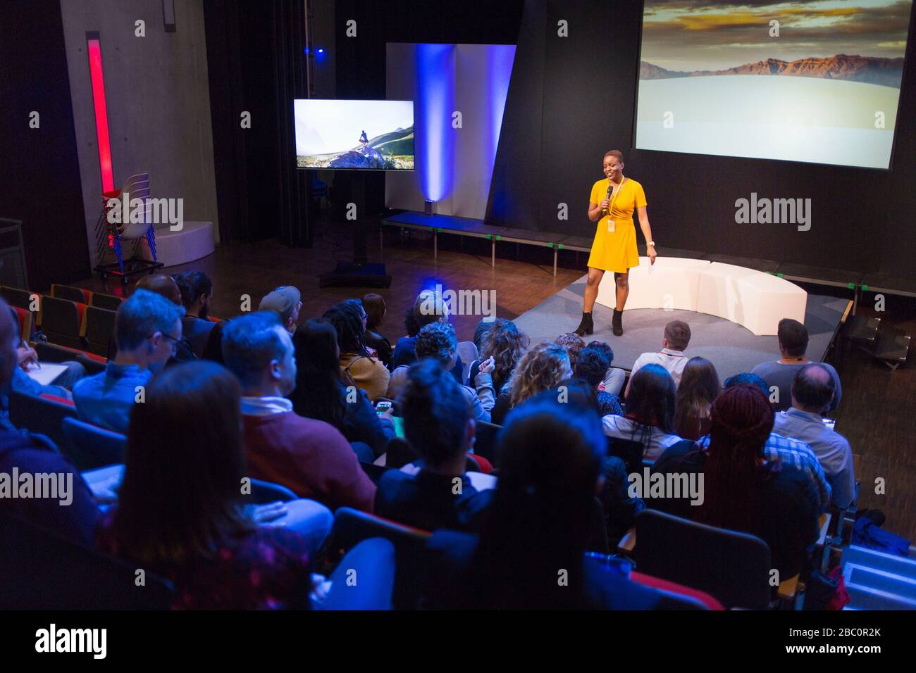 Altoparlante femmina sul palco che parla con il pubblico Foto Stock