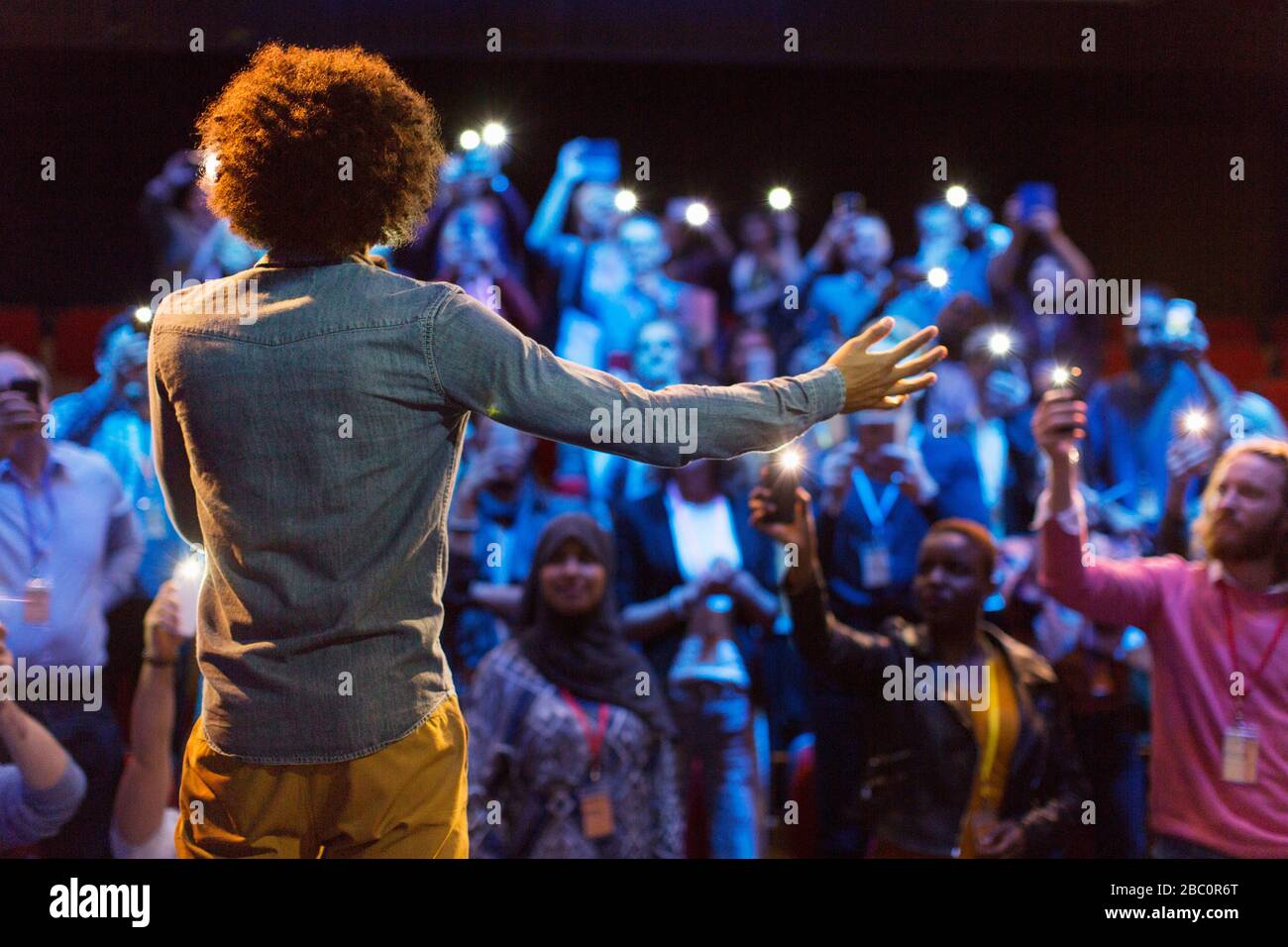 Altoparlante sul palco che parla con il pubblico con le torce dello smartphone Foto Stock