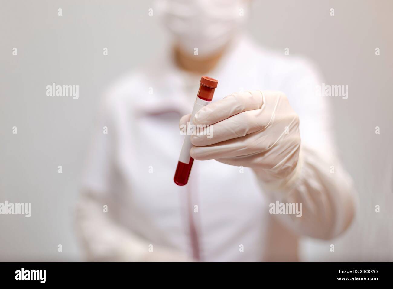 Medico con maschera e guanti che tengono una provetta di analisi medica, sangue e luogo per il testo Foto Stock