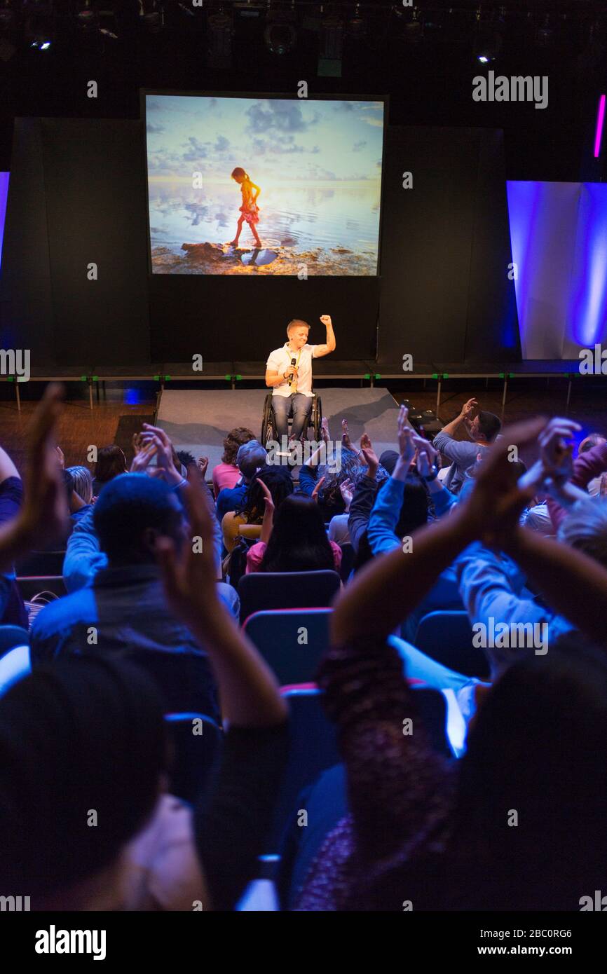 Il pubblico si aggrae per l'altoparlante femminile in sedia a rotelle sul palco Foto Stock