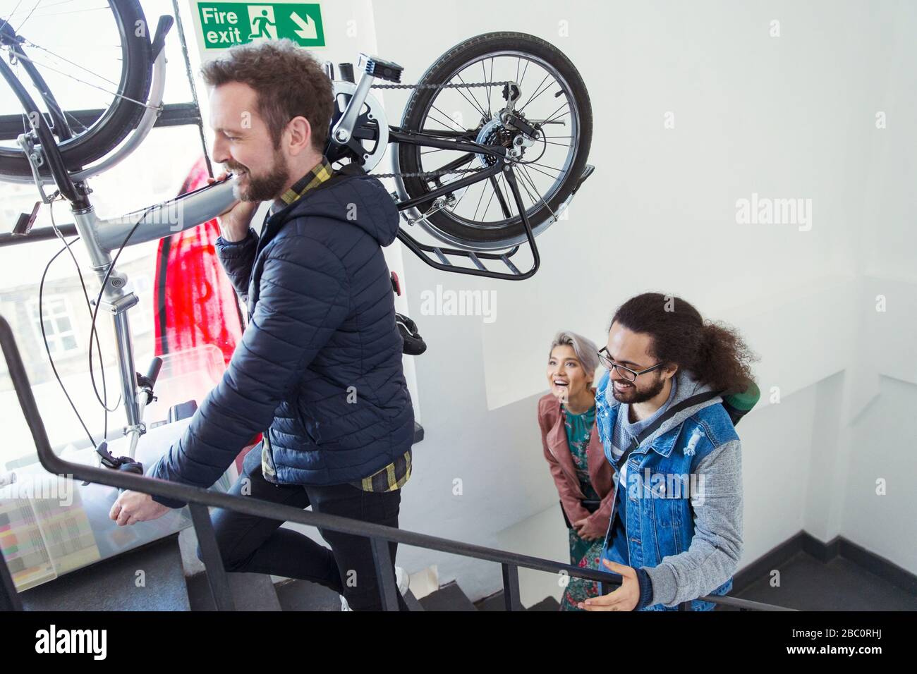 Amici che portano la bicicletta su scala Foto Stock