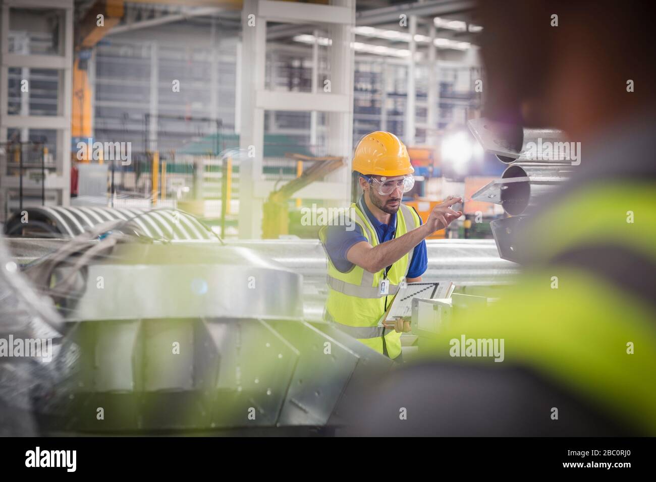 Lavoratore maschio che punta, lavorando in fabbrica di acciaio Foto Stock