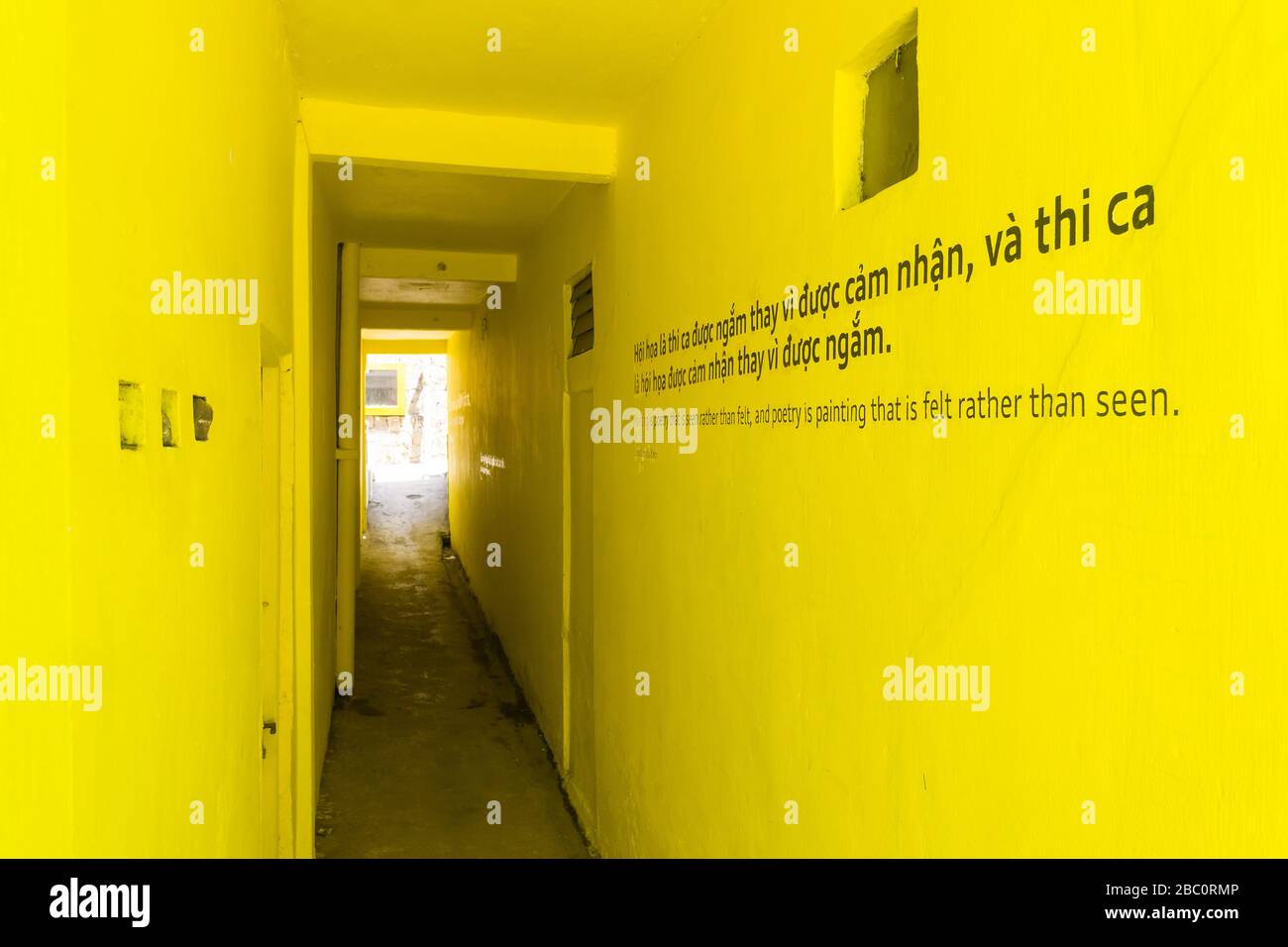 Corridoio giallo brillante con righe di poesia vietnamita dipinte sul muro a Da Lat, Vietnam. Foto Stock