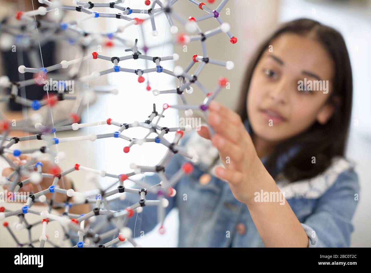 Studentessa studentesca che esamina e tocca la struttura molecolare in classe Foto Stock