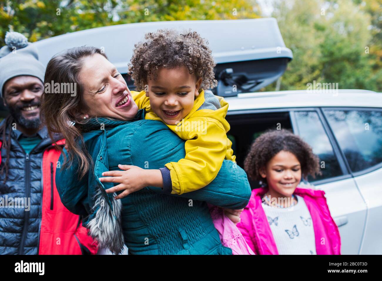 Madre e figlia felici che si abbracciano fuori auto Foto Stock