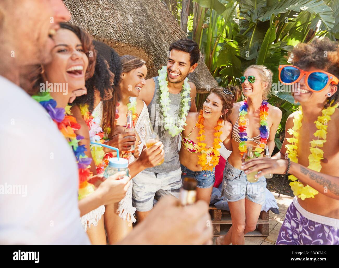 Giovani amici che indossano leis, appendere fuori alla piscina estiva Foto Stock