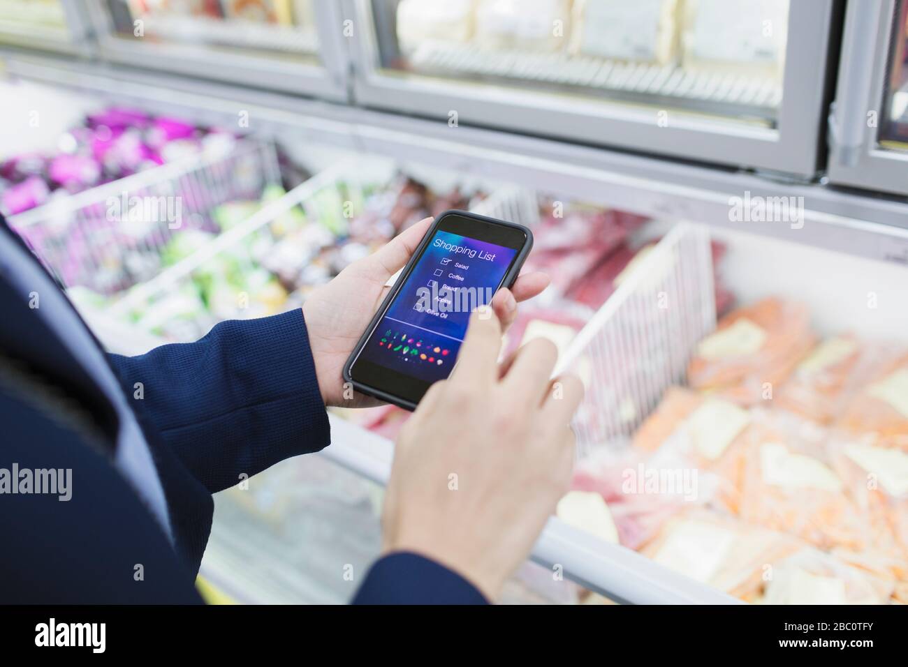 Donna che usa l'applicazione della lista di shopping, shopping nel supermercato Foto Stock