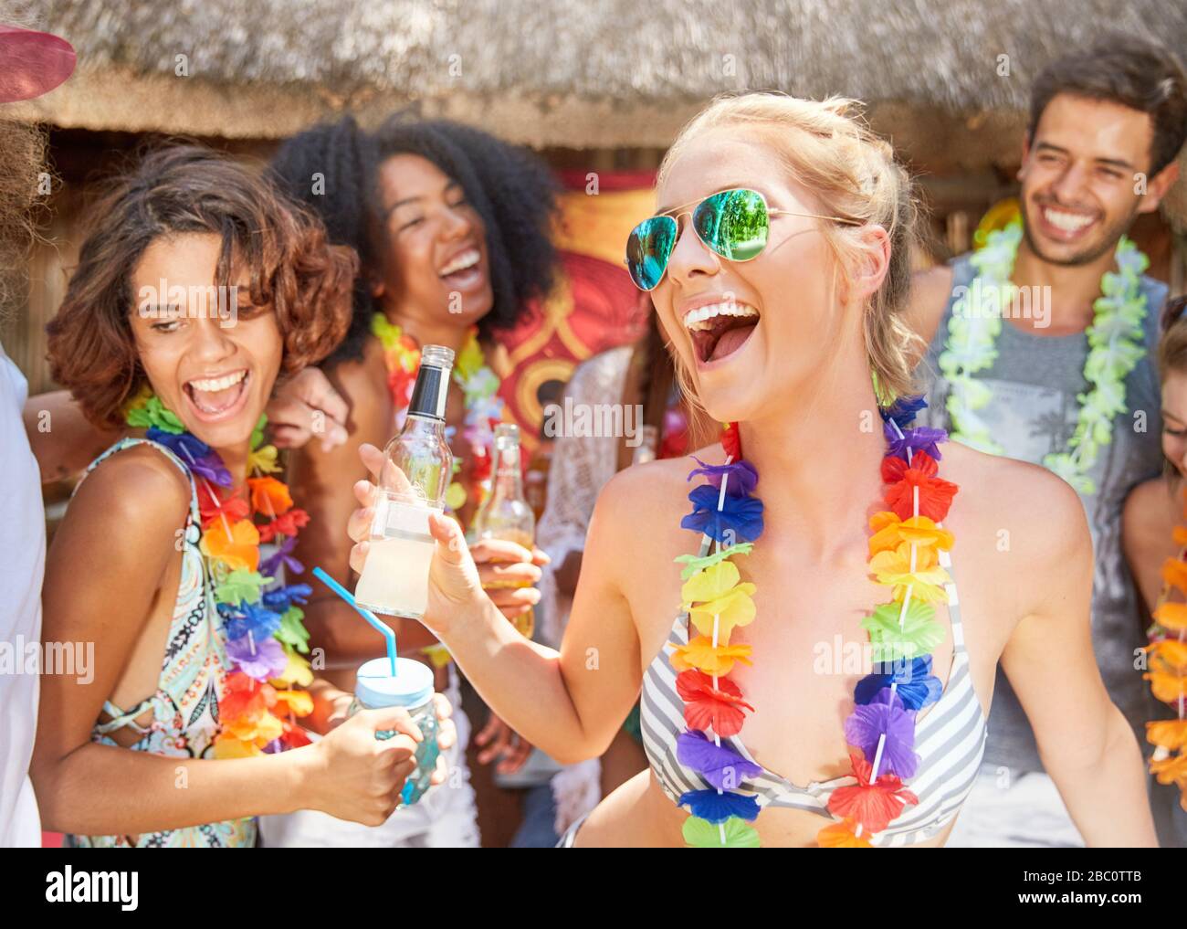 Amici giocosi che indossano il lebbroso e festeggiano nella soleggiata piscina estiva Foto Stock