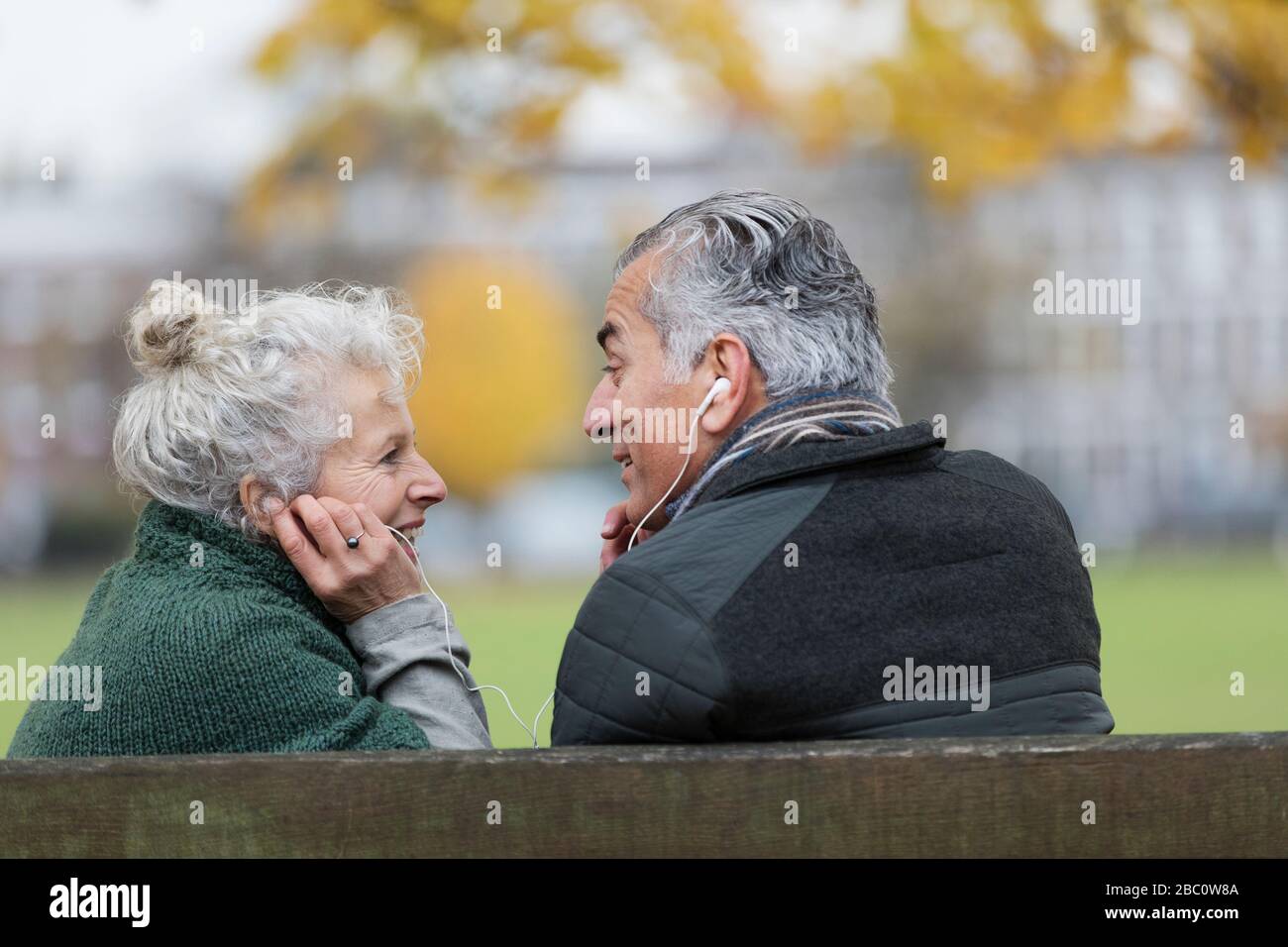 Felice coppia senior che condivide le cuffie, ascoltando musica nel parco Foto Stock