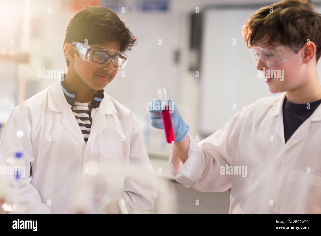 Ragazzi studenti che esaminano il liquido in provetta, conducendo esperimenti scientifici in classe di laboratorio Foto Stock
