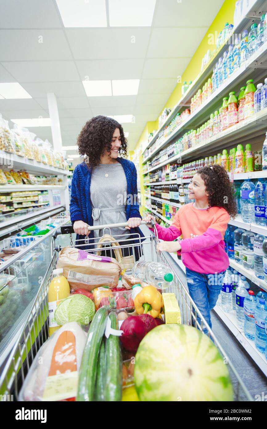 Madre e figlia che spingono il carrello nel supermercato Foto Stock