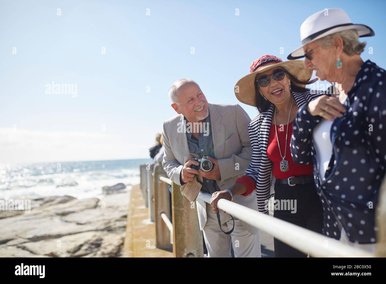 Attivi amici turistici senior al soleggiato oceano vista Foto Stock