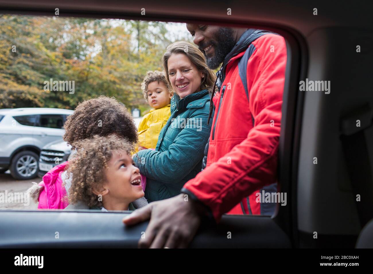 Felice famiglia multietnica fuori auto Foto Stock