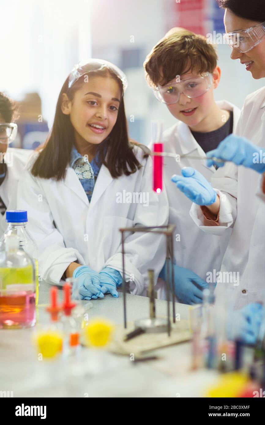 Studenti curiosi che conducono esperimenti scientifici, guardando il liquido in fiala in classe di laboratorio Foto Stock