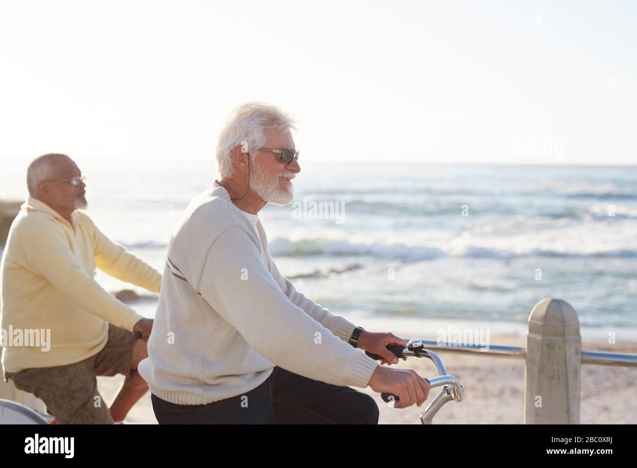 Guida in bici attiva per uomini senior, con vista sull'oceano Foto Stock