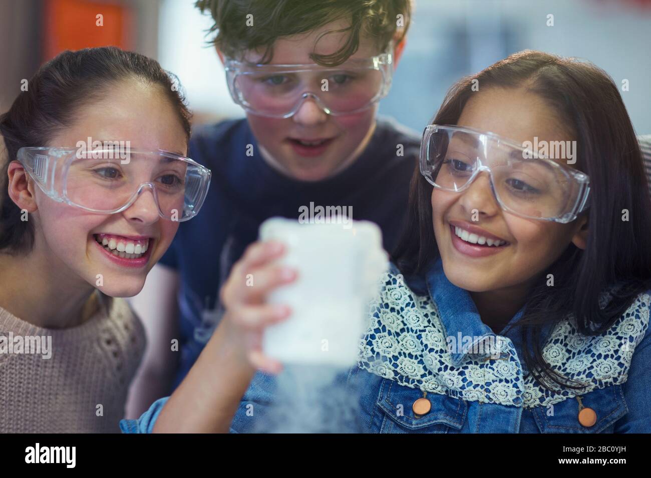 Studenti curiosi e sorridenti che guardano la reazione chimica, conducendo esperimenti scientifici in classe di laboratorio Foto Stock