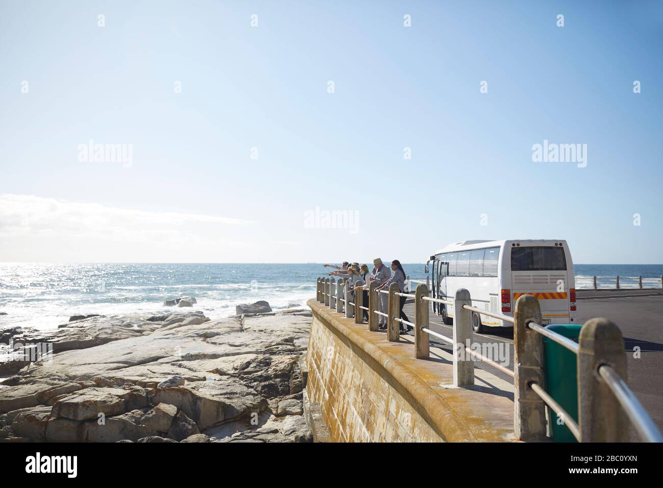 Turisti che guardano all'oceano soleggiato vista fuori bus tour Foto Stock