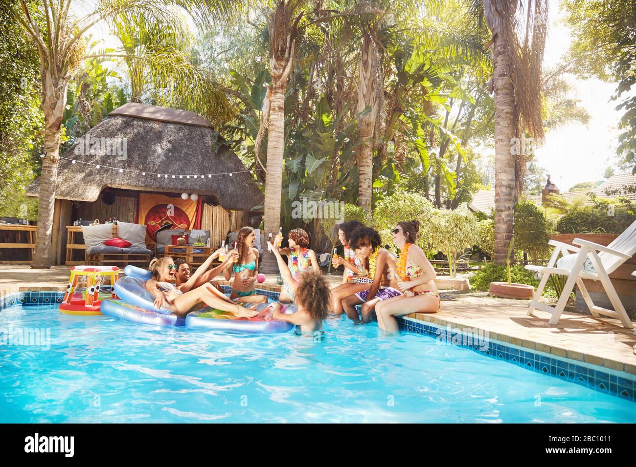 Giovani amici che si aggrappano alla piscina tropicale estiva Foto Stock