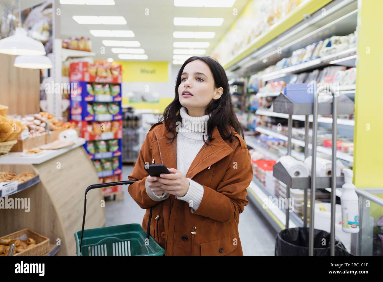 Donna con smart phone shopping in supermercato Foto Stock