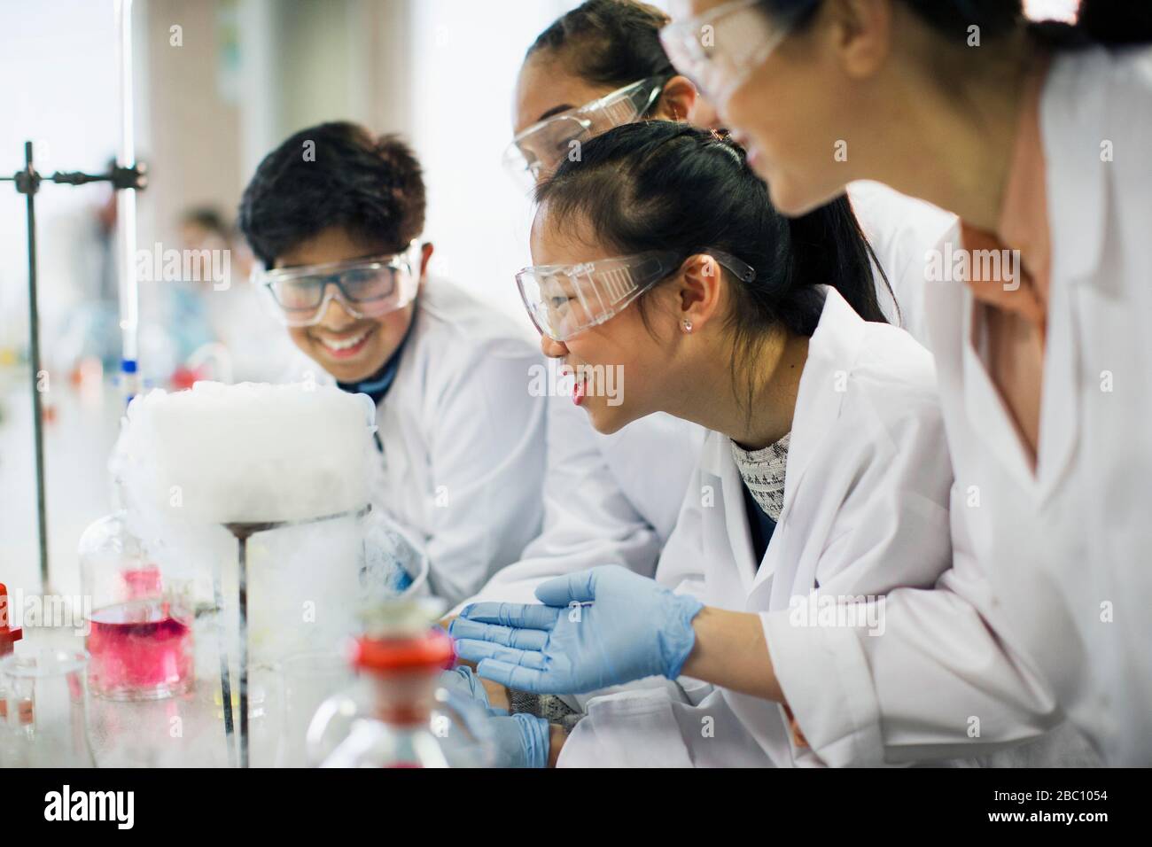 Studenti curiosi che osservano la reazione chimica, conducendo esperimenti scientifici in classe di laboratorio Foto Stock