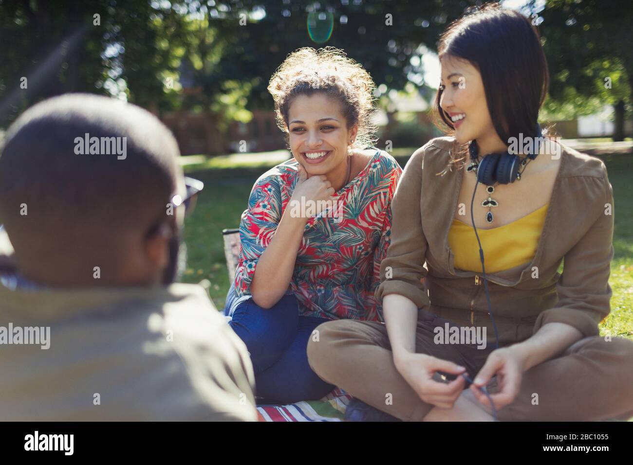 Sorridendo giovani amici che parlano, appendere fuori nel parco estivo soleggiato Foto Stock