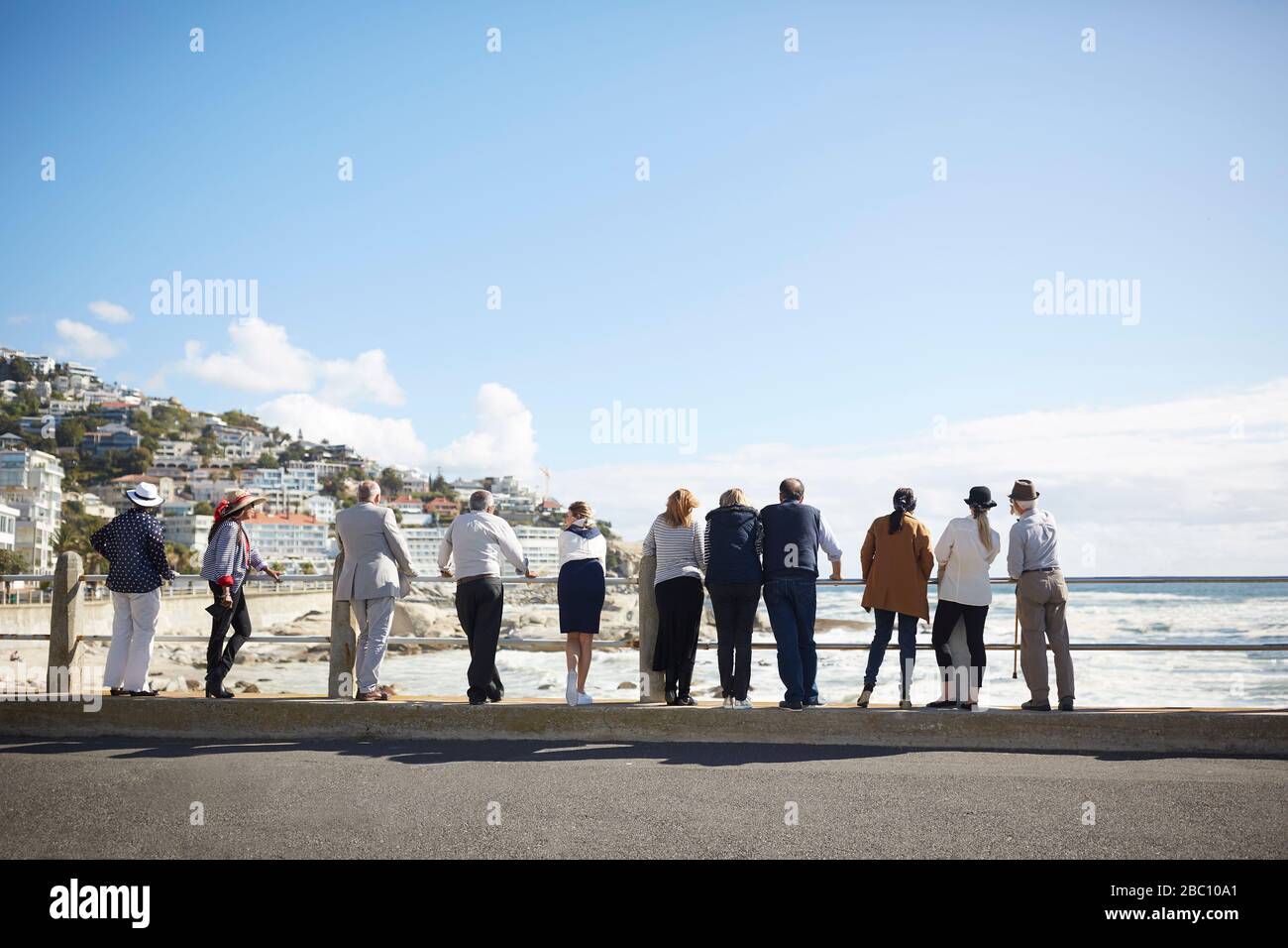 Amici turistici senior attivi che guardano all'oceano soleggiato vista Foto Stock