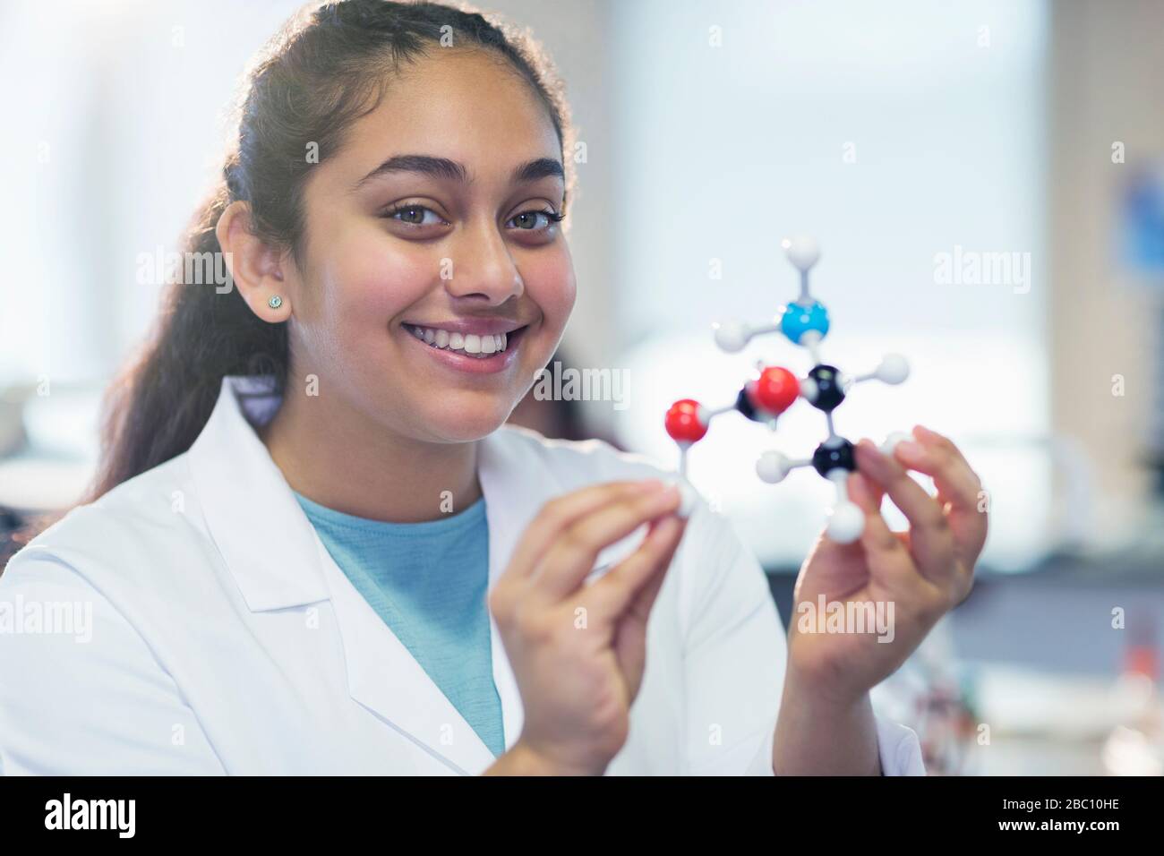 Ritratto ragazza sorridente studente che tiene modello molecolare in classe di laboratorio Foto Stock