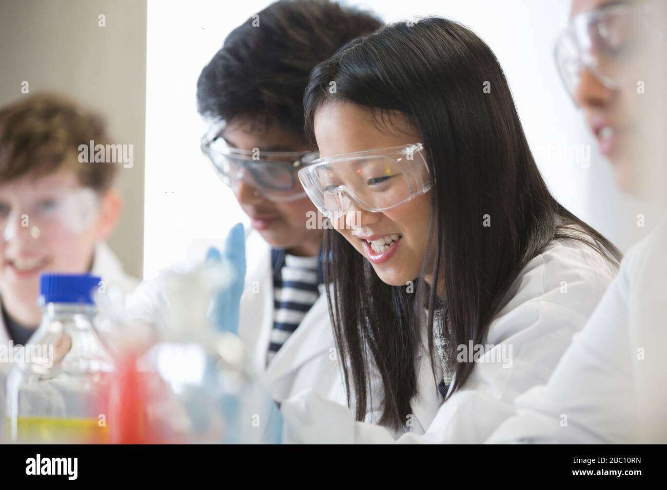 Ragazza sorridente che conduce esperimenti scientifici in classe di laboratorio Foto Stock