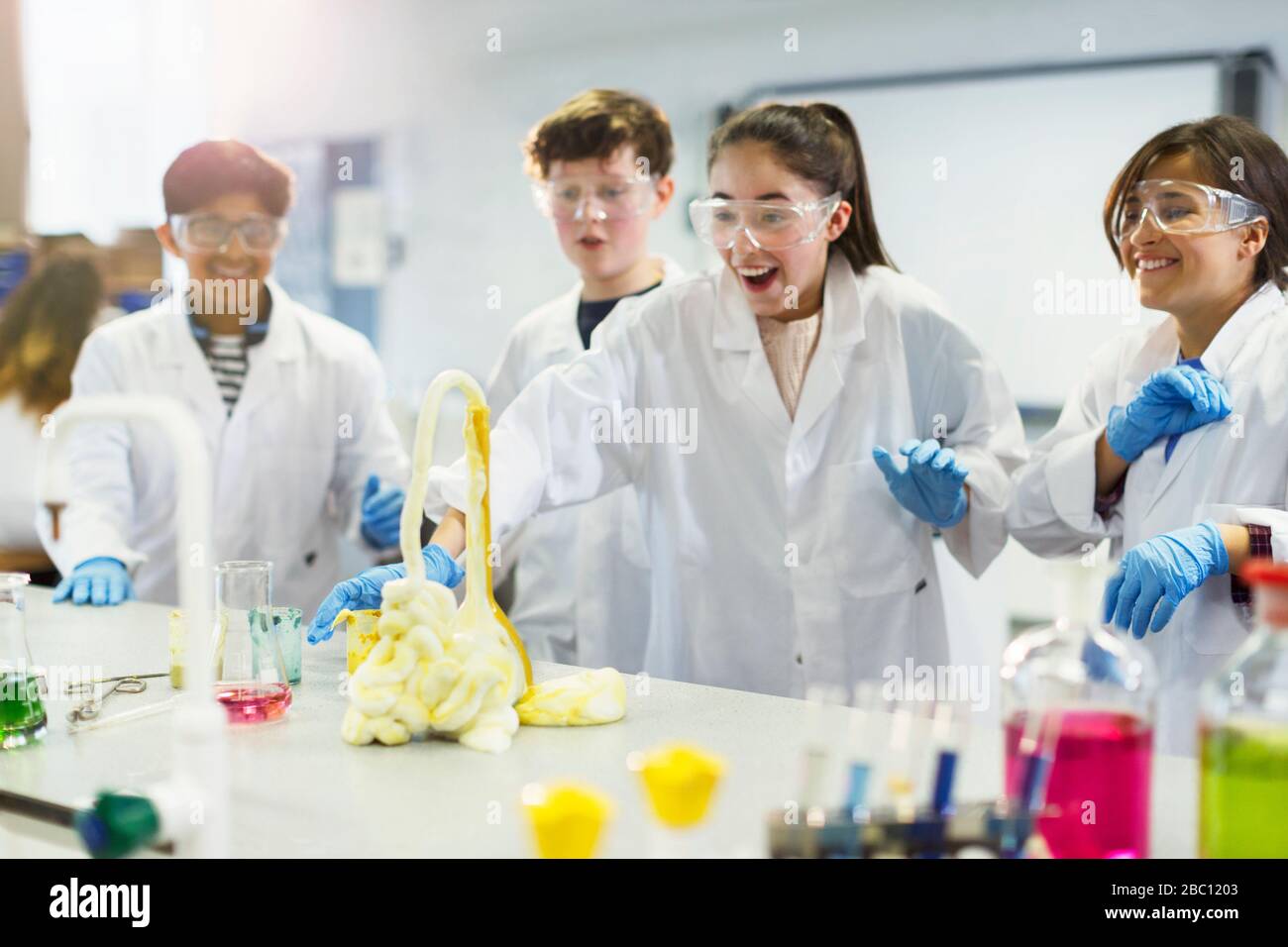 Studenti sorpresi che conducono esperimenti scientifici di schiuma esplosivi in laboratorio in classe Foto Stock