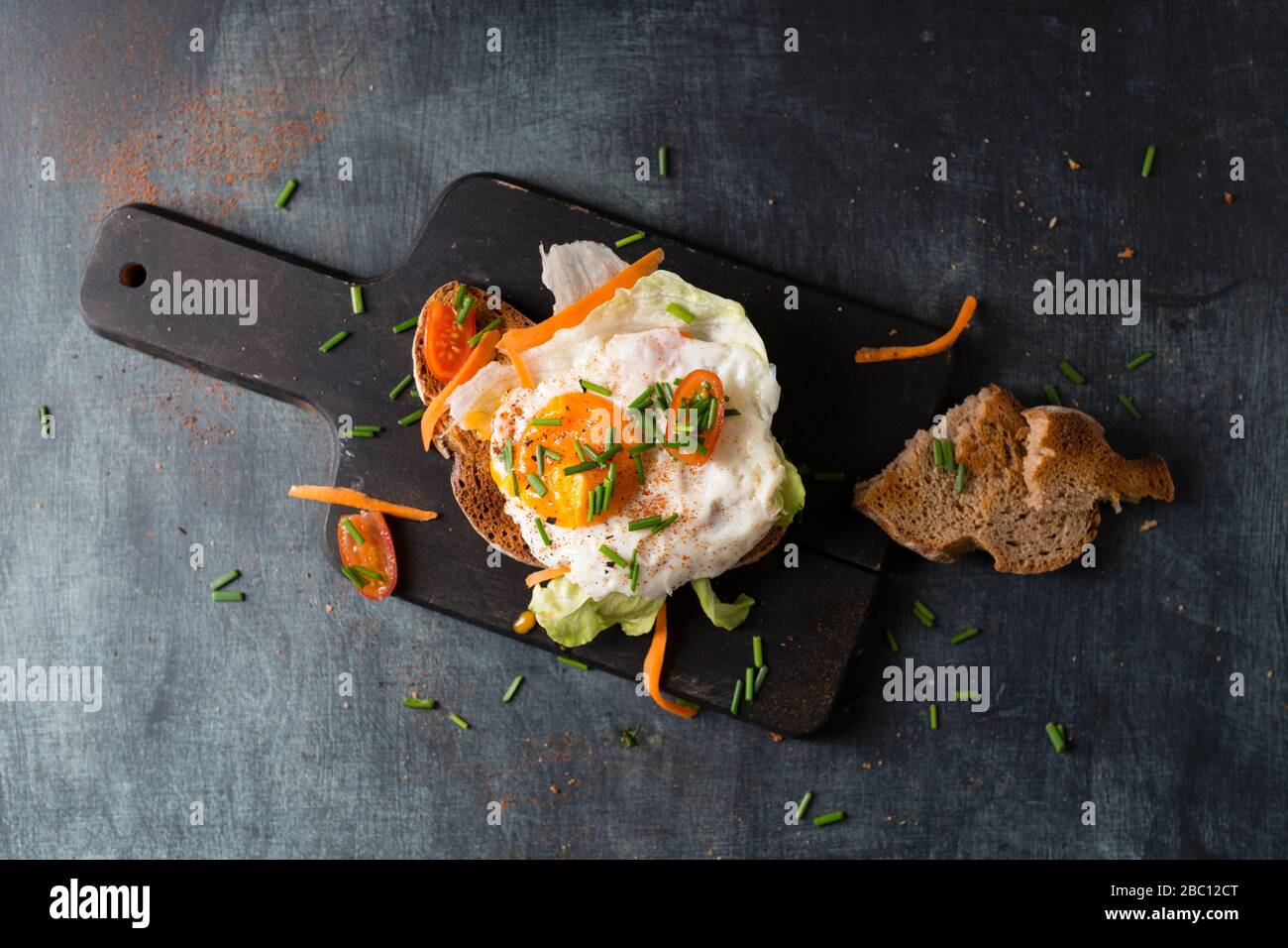 Uovo fritto con pane e verdure sdraiati sul tagliere Foto Stock
