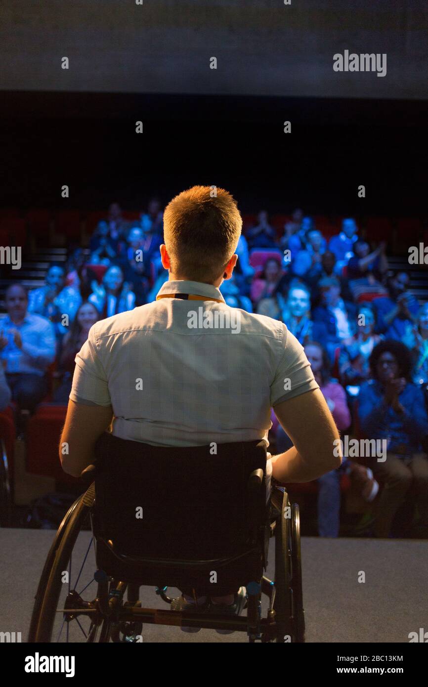 Altoparlante femminile in sedia a rotelle sul palco che parla con il pubblico Foto Stock
