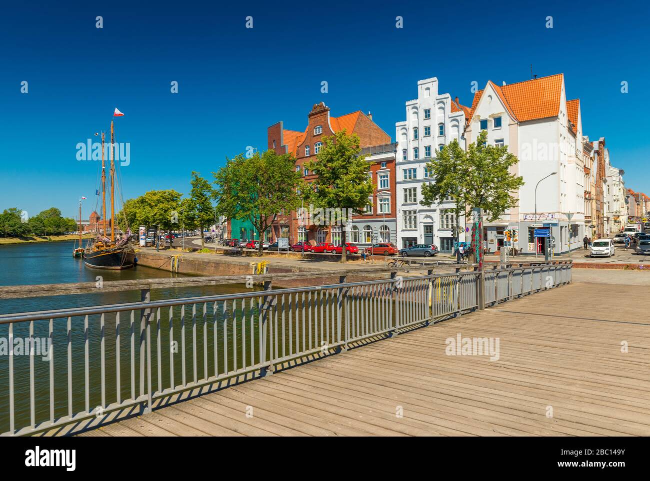 Lubecca (Lübeck) - Luglio 2018, Germania: Paesaggio urbano della vecchia città europea con edifici storici, nave in legno e ponte sul fiume Trave Foto Stock