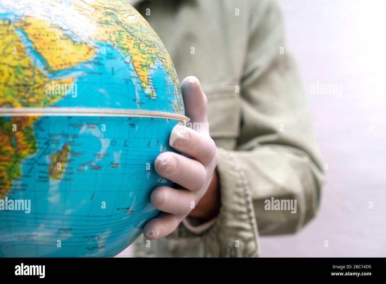 Mano con guanto protettivo, toccando il globo Foto Stock