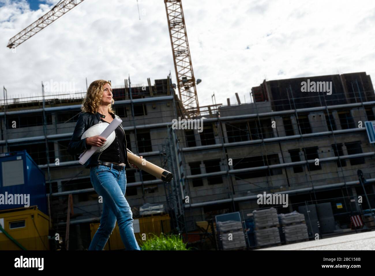 Architetto femminile con casco e piano di costruzione in cantiere Foto Stock