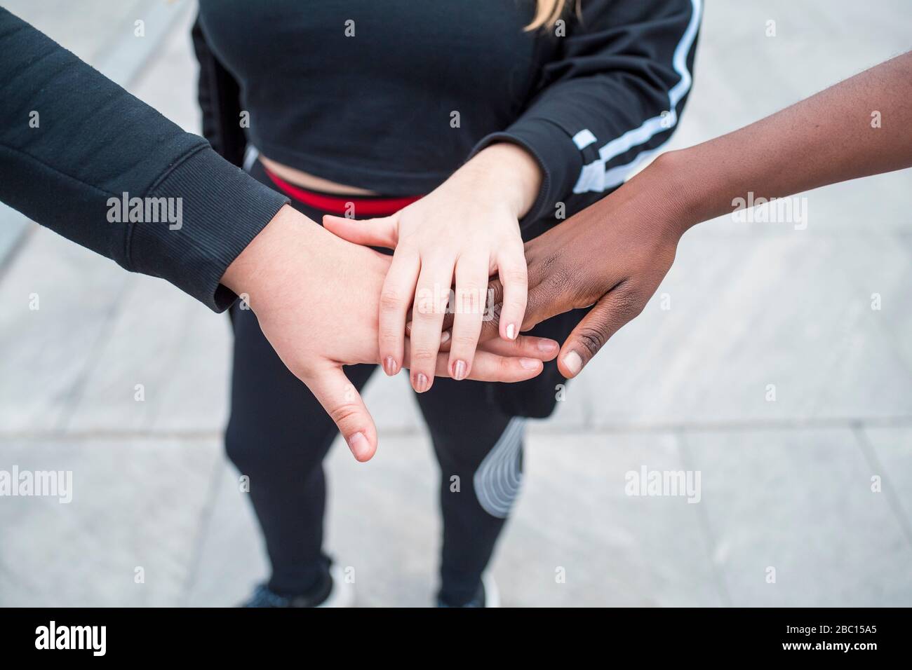Chiudi -p di tre donne sportive che si accatastano le mani Foto Stock