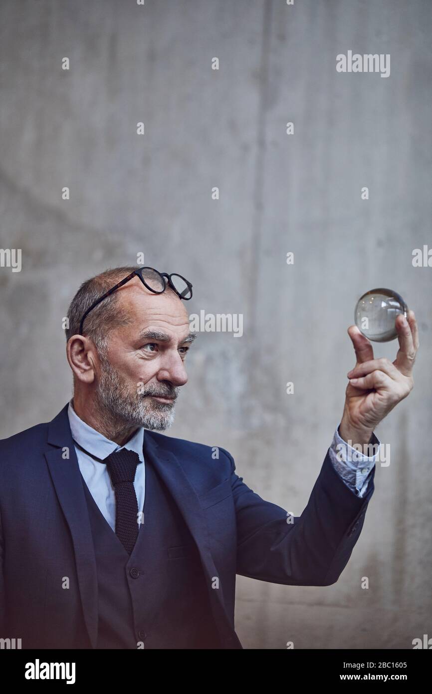 Uomo d'affari senior che guarda la palla di cristallo Foto Stock