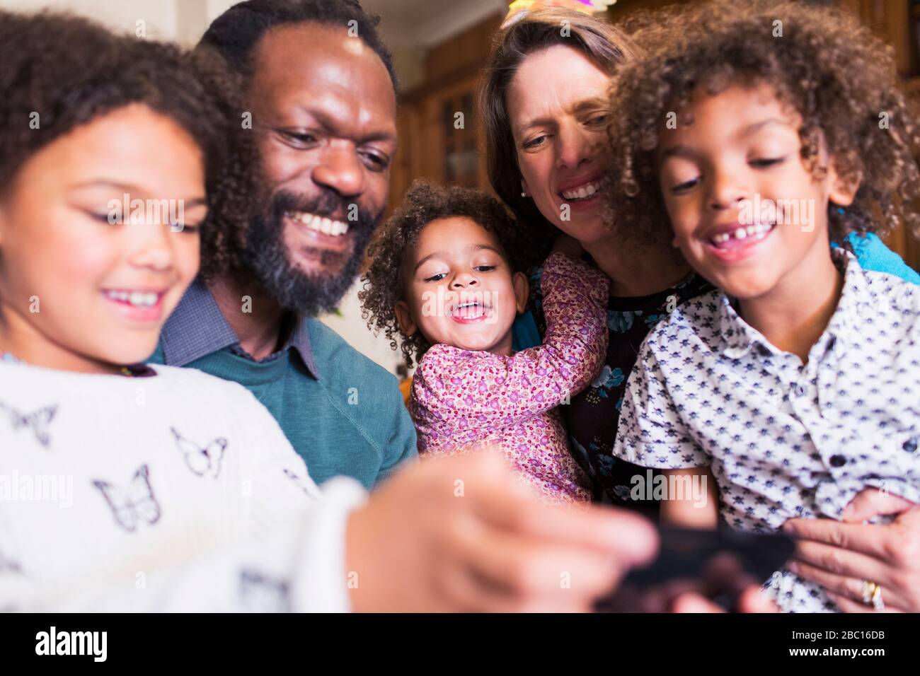 Famiglia multietnica felice con smartphone Foto Stock