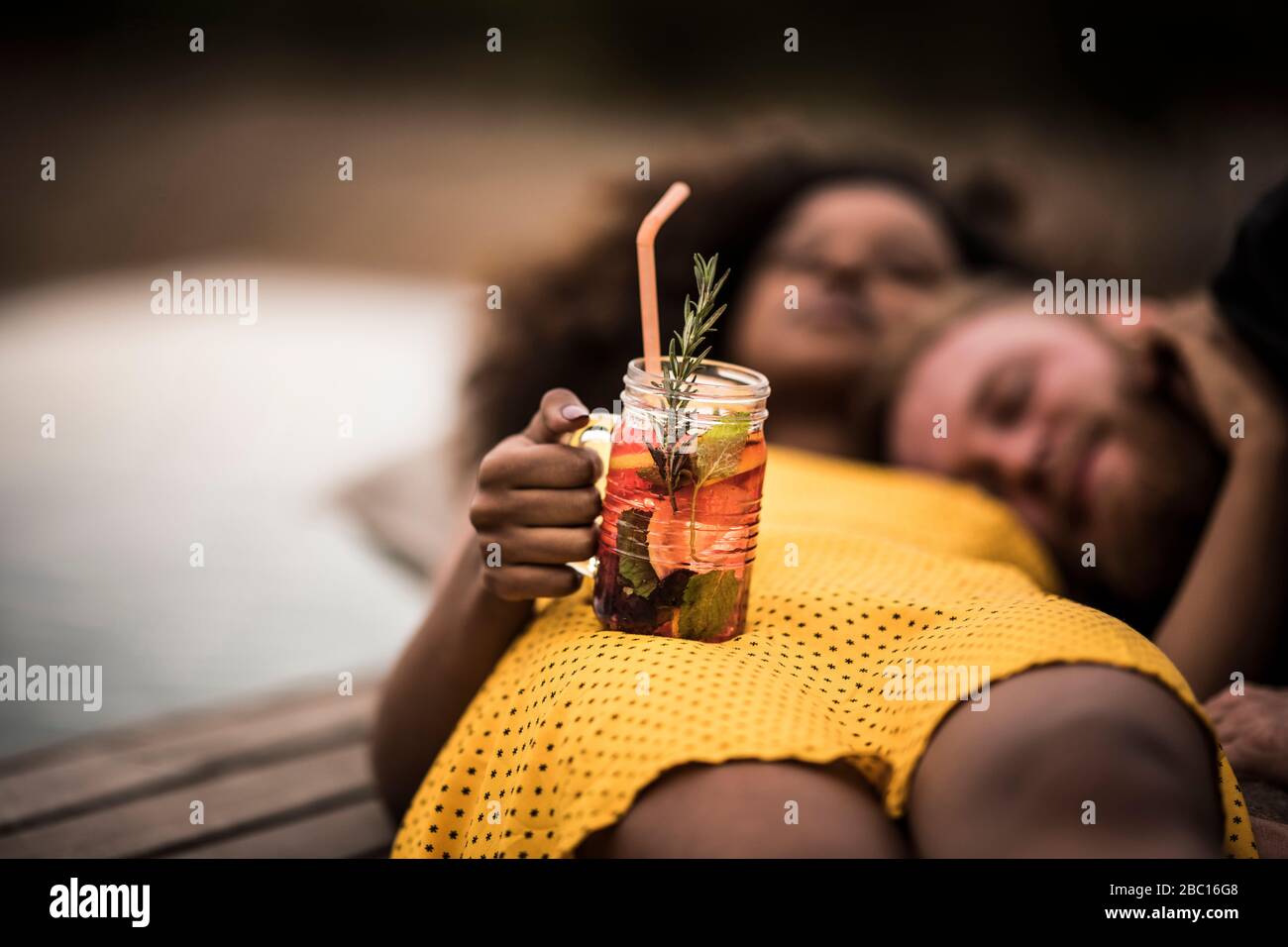 Giovane donna che si trova a terra con il suo ragazzo tenendo fresco tè bevanda ghiaccio Foto Stock