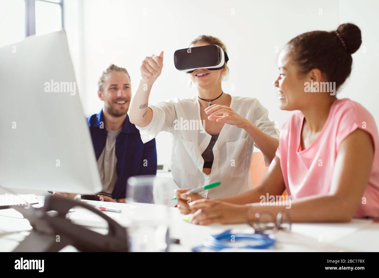 Programmatori di computer che testano occhiali simulatori di realtà virtuale al computer in ufficio Foto Stock