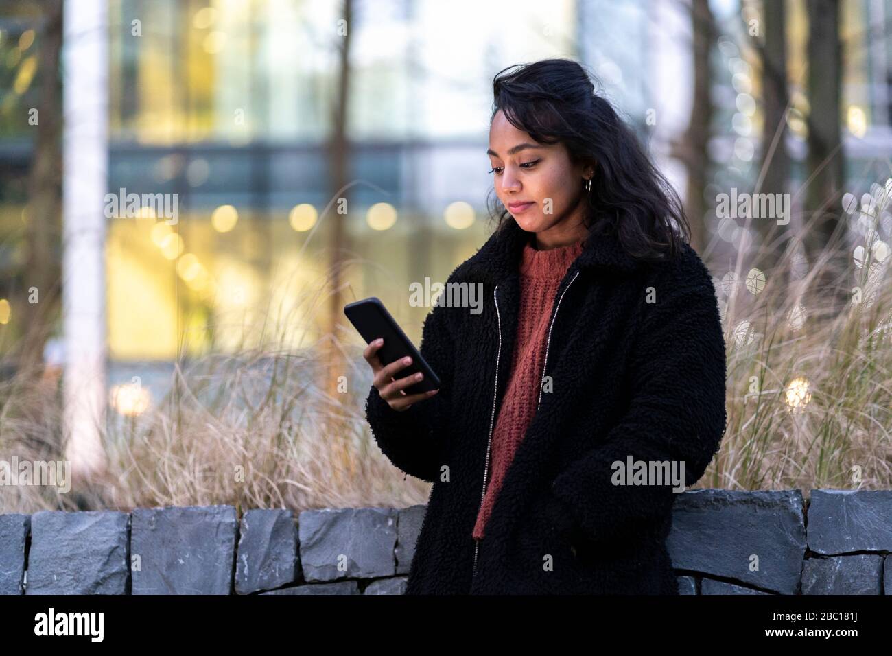 Giovane donna utilizzando il cellulare in città Foto Stock